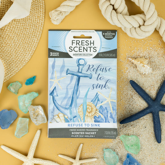 Fresh Scents' Refuse To Sink - Sachet 3pk features nautical designs and offers flameless fragrance. Displayed on sandy yellow with seashells, sea glass, rope, a starfish, and sun hat for a beach-inspired vibe.