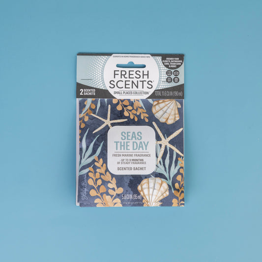 The Fresh Scents Seas the Day - Sachet 2pk features a marine design with seashells, starfish, and seaweed on blue. These flameless sachets provide long-lasting fragrance for small spaces and are shown on a solid light blue surface.