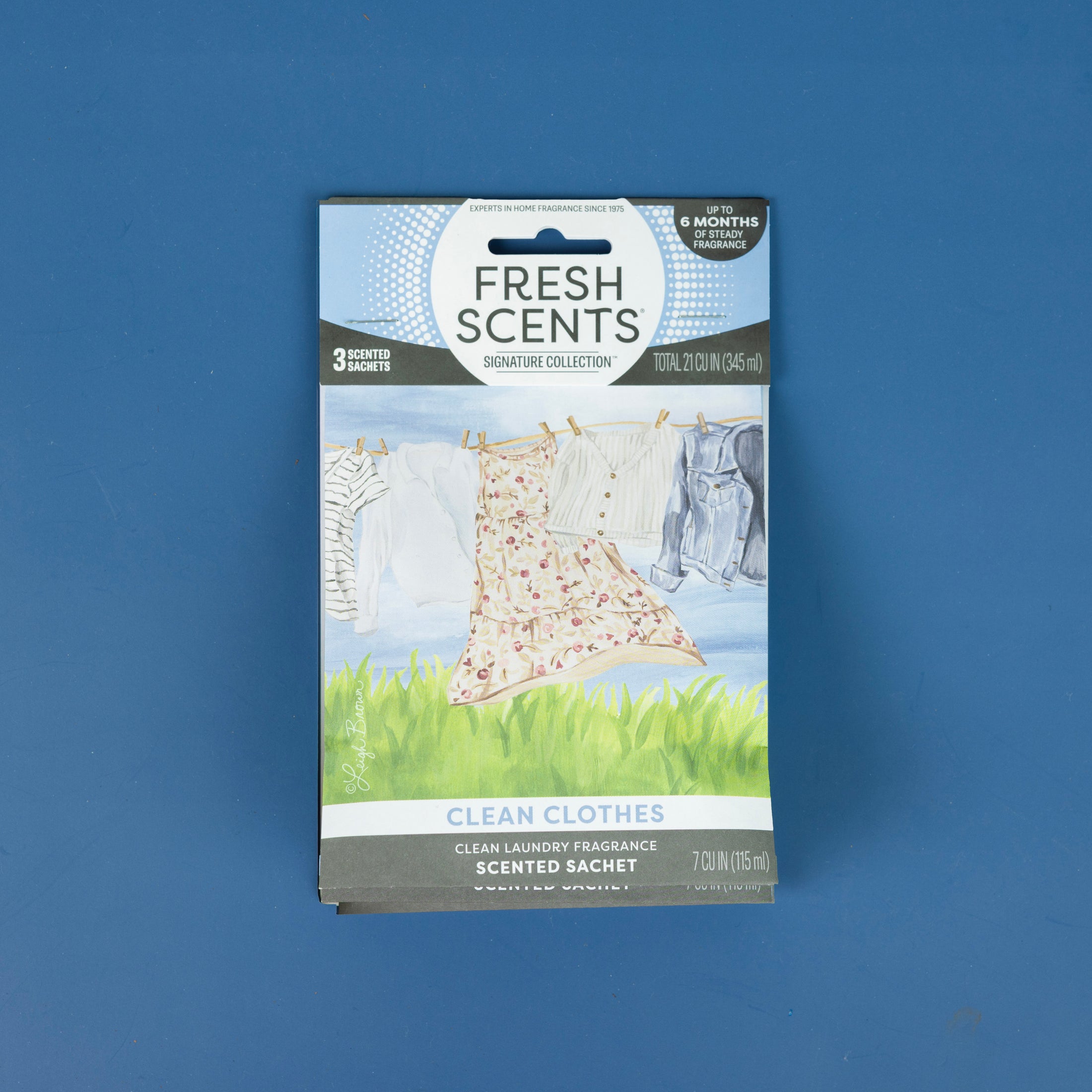 The Fresh Scents Clean Clothes - Sachet 3pk is displayed against a blue background, with packaging showing clothes on a clothesline to illustrate this flameless, long-lasting air freshener.