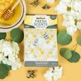 Load image into Gallery viewer, The Fresh Scents Bee Happy - Sachet 3pk features long-lasting air fresheners with honeycomb and bee designs, white flowers, green leaves, a bowl of honey, and bee charms on a sunny yellow background.
