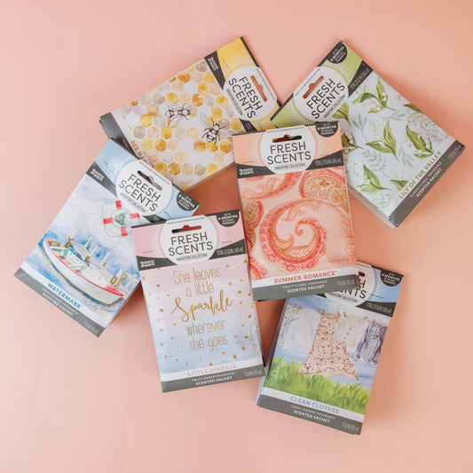 Six Bestsellers Bundle scented sachets by Fast Bundle in colorful packs are displayed on a light pink surface. Scents featured include Watermark, Clean Clothes, Summer Romance, Little Sparkle, and two additional fragrances.