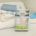 Load image into Gallery viewer, A Fresh Scents Clean Clothes - Sachet 3pk rests before folded towels, a blue cloth, and laundry supplies on a light surface, adding a flameless fragrance for a fresh and clean laundry scene.
