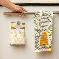 Load image into Gallery viewer, A hand hangs a "Home Sweet Home" bee and floral towel next to Fresh Scents' Bee Happy Sachet 3pk—a flameless air freshener for long-lasting fragrance.
