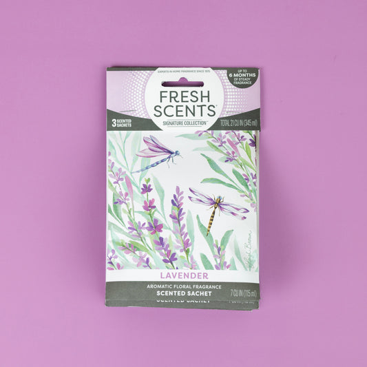 A Fresh Scents Lavender - Sachet 3pk is displayed on a pink background, with packaging decorated by lavender flowers and two dragonflies, promoting flameless fragrance and long-lasting air freshener benefits.