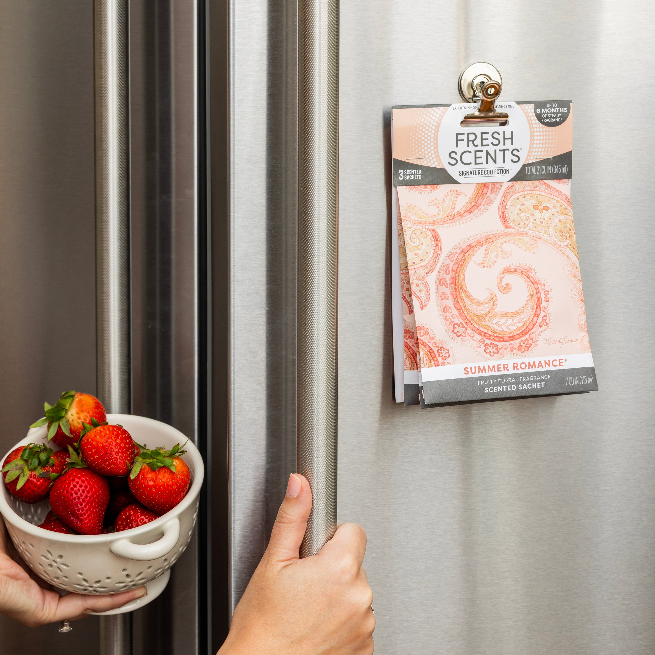 A hand holds a bowl of strawberries, capturing the fresh, fruity aroma of Fresh Scents Summer Romance Sachet 3pk air fresheners.