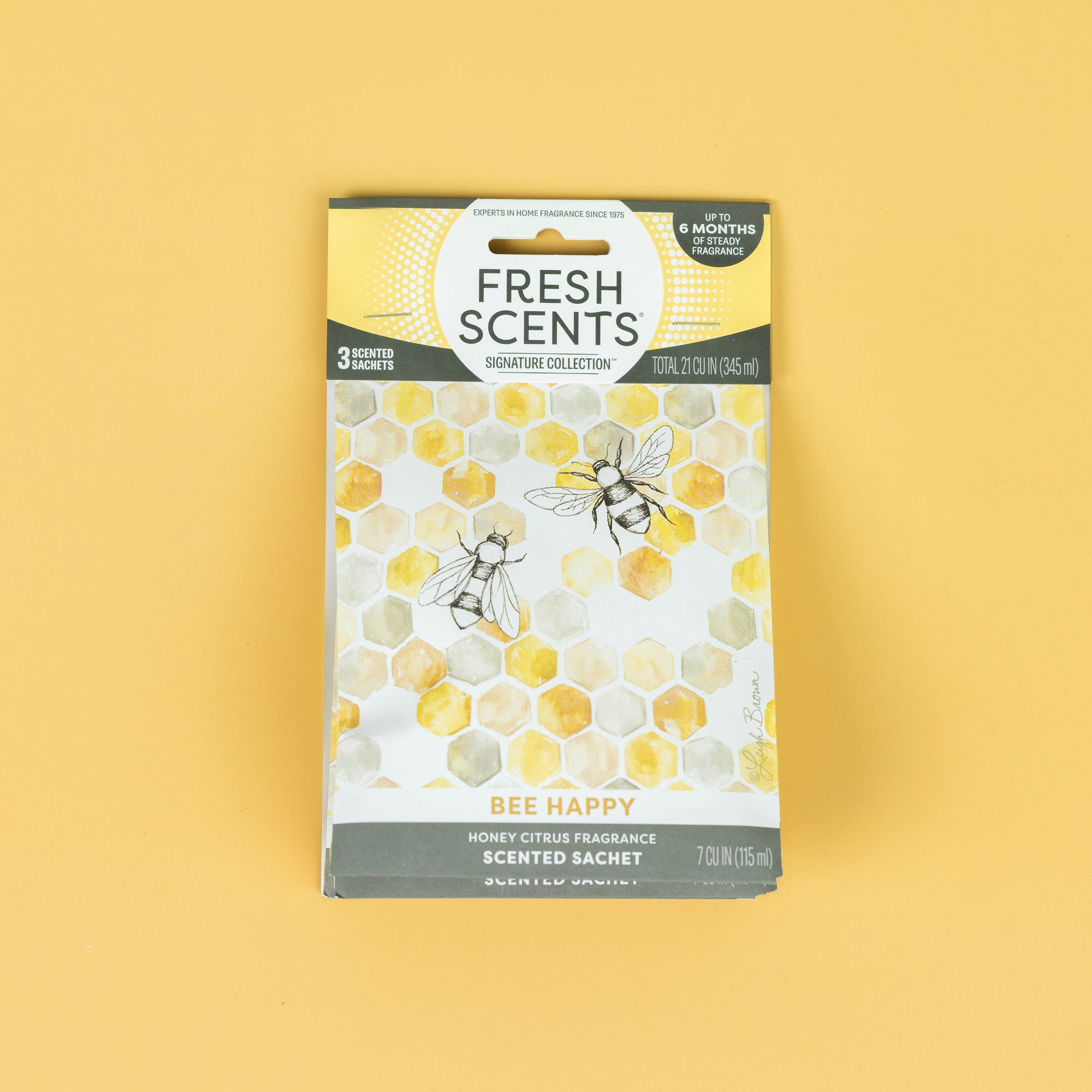 The Fresh Scents Bee Happy - Sachet 3pk features a honeycomb and bee design on yellow, with a honey citrus flameless fragrance. Each pack contains three long-lasting air freshener sachets that last up to six months.