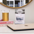 Load image into Gallery viewer, A desk with a closed laptop, books, a gold pen holder, and a Fresh Scents Do What You Love - Sachet 3pk in front of a round mirror—a stylish, flameless way to keep your room fresh for longer.
